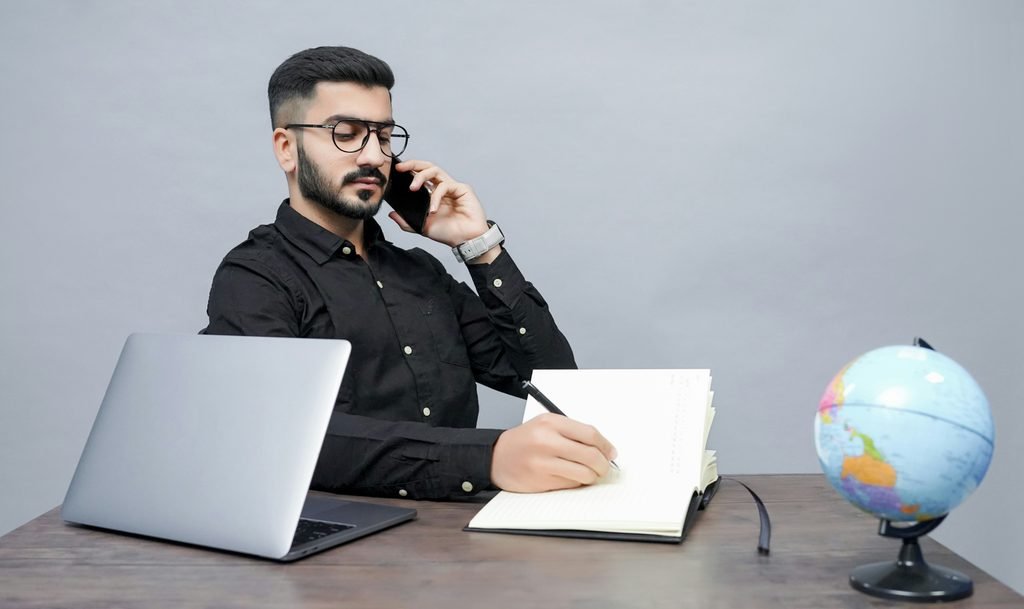 Person taking notes before a phone call, representing preparing to negotiate a lower interest rate