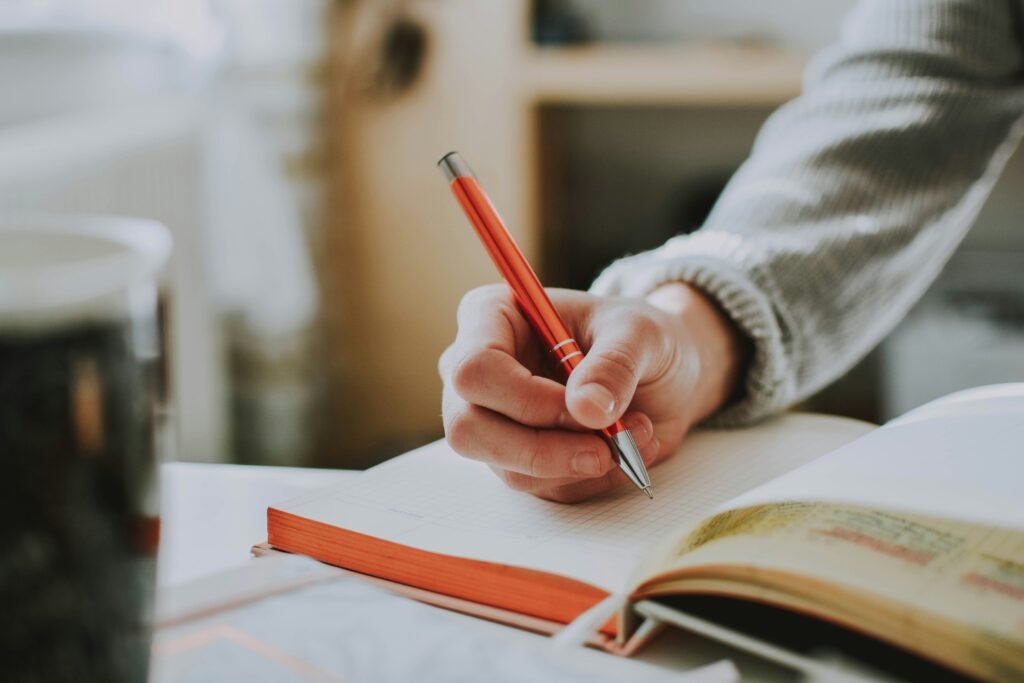 Person writing specific financial goals in a notebook