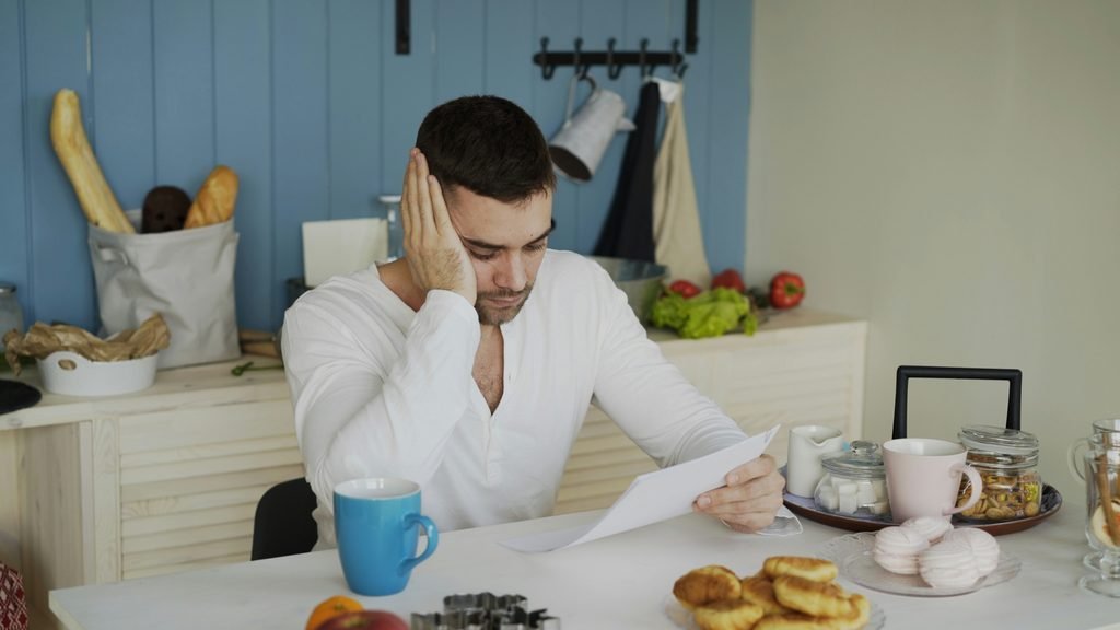 Stressed person reading a bill letter, representing an unexpected tax bill