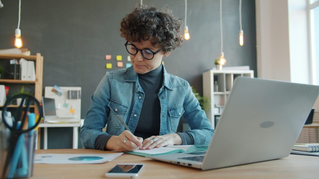 Young professional reviewing paperwork on laptop, representing checking your 401k match